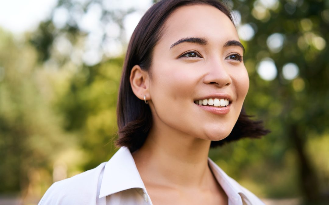 Close up face of asian happy girl, smiling and looking at camera carefree, walking in park