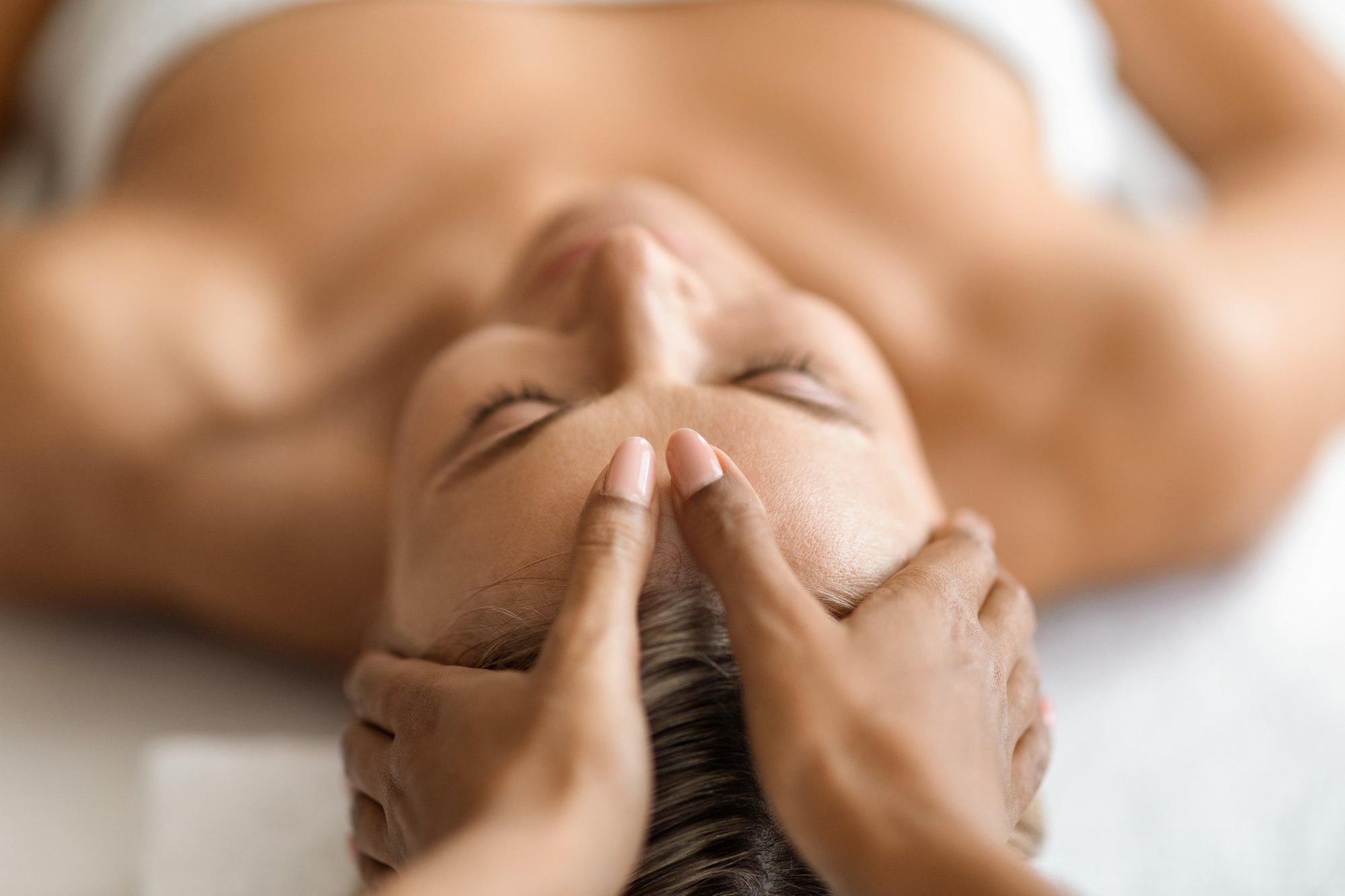Closeup of hands massaging beautiful woman's face at spa salon Closeup of hands massaging beautiful woman's face at spa salon